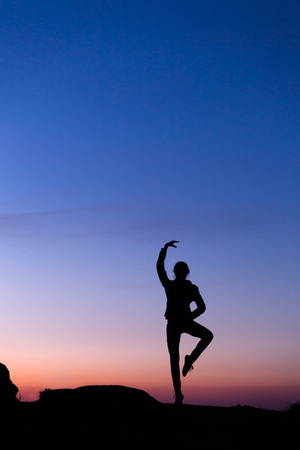 Silhouette of happy young woman against beautiful colorful sky. Summer Sunset. Landscapeの写真素材
