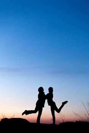 Silhouettes of mother and daughter at the beautiful sunset. Dusk. Summer Landscapeの写真素材