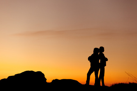 Silhouettes of mother and daughter at the beautiful sunset. Dusk. Summer Landscapeの写真素材