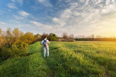 Beautiful sunset. Spring landscape with man on the fieldの写真素材