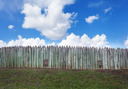 Old wooden fence against blue sky with clouds. Background for design