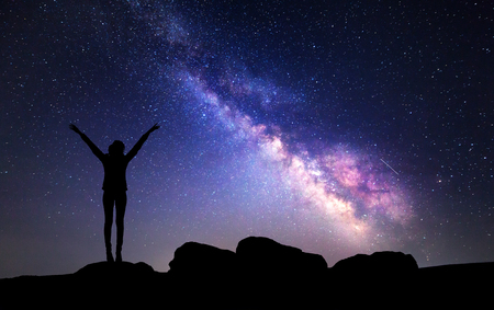 Milky Way. Night sky with stars and silhouette of a woman with raised-up arms.の写真素材