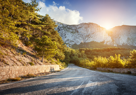 Asphalt country road in mountains with beautiful blue sky in summer at sunsetの写真素材