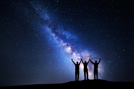 Landscape with colorful Milky Way and silhouette of a happy family with raised-up arms on the mountain. Night starry sky. Beautiful Universe. Space backgroundの写真素材