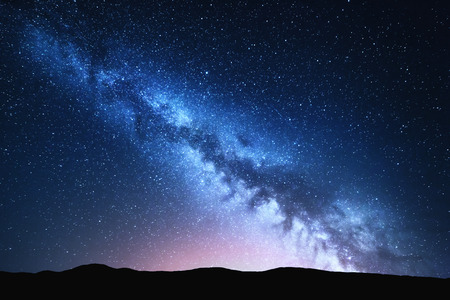 Milky Way and pink light at mountains. Night colorful landscape. Starry sky with hills at summer. Beautiful Universe. Space background with galaxy. Travel backgroundの写真素材