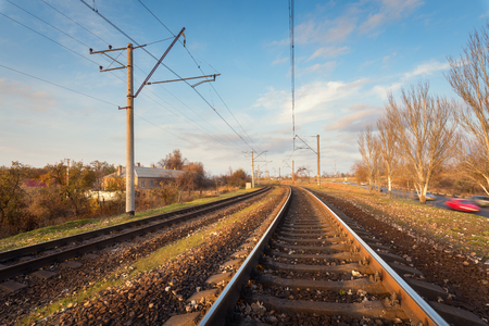 Railroad against beautiful sky at sunset. Industrial landscape with railway station, colorful blue sky, trees and grass, cars in motion. Railway junction. Heavy industry. Railways. Cargo shippingのeditorial素材