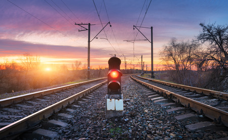 Railway station with semaphore against sunny sky with clouds at sunset. Colorful industrial landscape. Railroad. Railway platform with traffic light in the evening. Heavy industry. Cargo shippingの写真素材