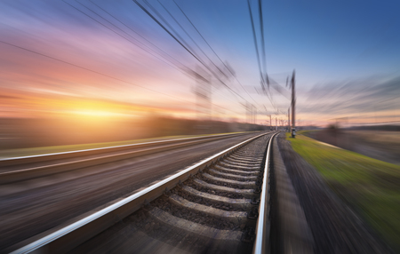 Railroad in motion at sunset. Railway station with motion blur effect against colorful blue sky, Industrial concept background. Railroad travel, railway tourism. Blurred railway. Transportationの写真素材