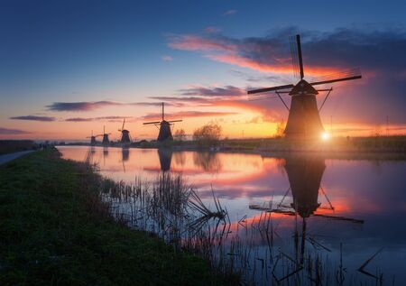 Silhouette of windmills at amazing foggy sunrise in Kinderdijk, Netherlands. Rustic landscape with dutch windmills near the canals and colorful sky reflected in water. Nature background. Travelの写真素材