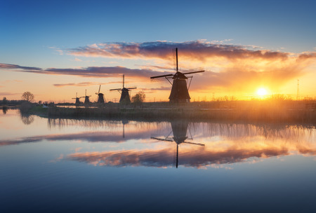 Silhouette of windmills at amazing foggy sunrise in Kinderdijk, Netherlands. Rustic landscape with dutch windmills near the canals and colorful sky reflected in water. Nature background. Travelの写真素材