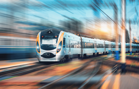High speed commuter train at the railway station at sunset in Europe. Modern intercity train on railway platform. Urban view with beautiful passenger train on railroad track. Railway transportationの写真素材