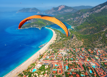 Paragliding in the sky. Paraglider tandem flying over the sea with blue water and mountains in bright sunny day. Aerial view of paraglider and Blue Lagoon in Oludeniz, Turkey. Extreme sport. Landscapeの写真素材