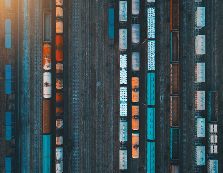 Aerial view of colorful freight trains on the railway station. Cargo trains close-up. Wagons with goods on railroad. Heavy industry. Industrial conceptual scene with trains. Top view. Vintage styleの写真素材