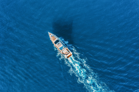 Yacht at the sea in Europe. Aerial view of luxury floating ship at sunset. Colorful landscape with boat in marina bay, blue sea. Top view from drone of yacht. Luxury cruise. Seascape with motorboatの写真素材