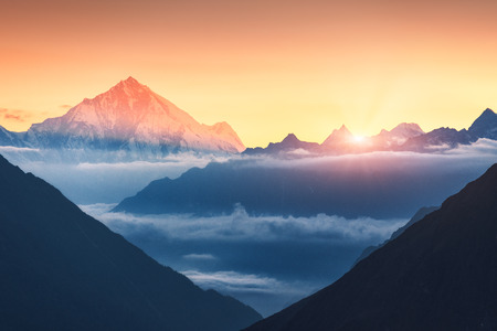 Majestic scene of silhouettes of mountains and low clouds at colorful sunrise in Nepal. Landscape with snowy peaks of mountains, beautiful sky and yellow sunlight. Rocks and sun rays.Nature backgroundの写真素材