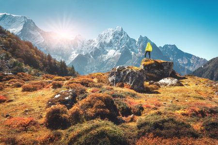 Standing man on the stone and looking on amazing Himalayan mountains at sunset. Landscape with traveler, high rocks with snowy peaks, plants, forest in autumn in Nepal. Lifestyle, travel. Trekkingの写真素材