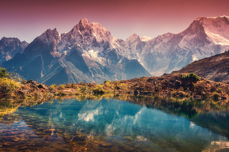 Beautiful landscape with high mountains with snow covered peaks, red sky reflected in lake. Mountain valley with reflection in water in sunset. Nepal. Amazing scene with Himalayan mountains. Natureの写真素材