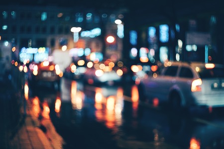 Blurred city at night. Bokeh. Beautiful abstract background with defocused buildings, cars, city lights, people. Colorful bokeh background with urban night scene. Design. Concept backdrop. Vintageの写真素材