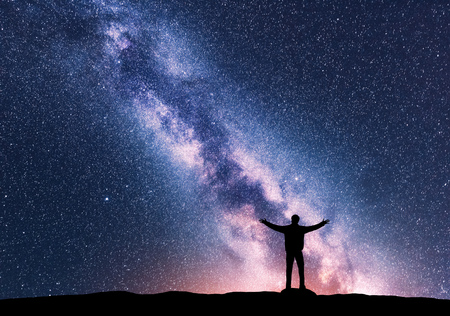 Milky Way and silhouette of a standing happy man with raised up arms. Travel in Nepal. Landscape with beautiful galaxy. Universe. Night sky with stars, colorful Milky Way. Starry sky and man. Spaceの写真素材