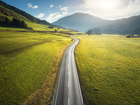 Aerial view of the road in mountain valley in Dolomites, Italy. Top view of perfect asphalt roadway, meadows with green grass, hills in autumn. Highway through the fields. Trip in europe. Travelの写真素材