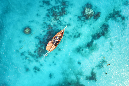 Aerial view of the fishing boats in clear blue water at sunset in summer. Top view from drone of boat, sandy beach. Indian ocean. Travel in Zanzibar, Africa. Landscape with sailboats, sea. Seascapeの写真素材