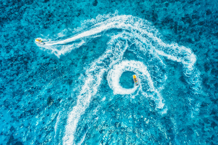 Aerial view of floating water scooter in blue water at sunset in summer. Holiday in Indian ocean, Zanzibar, Africa. Top view of jet ski in motion. Tropical seascape with moving motorboat. Extremeの写真素材