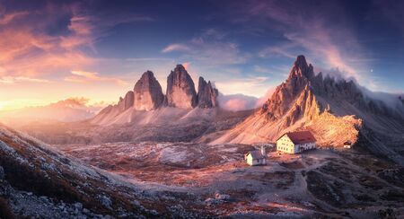 Mountain valley with beautiful house and church at sunset in autumn. Landscape with buildings, high rocks, colorful sky, clouds, sunlight. Mountains in Tre Cime park in Dolomites, Italy. Italian alpsの写真素材
