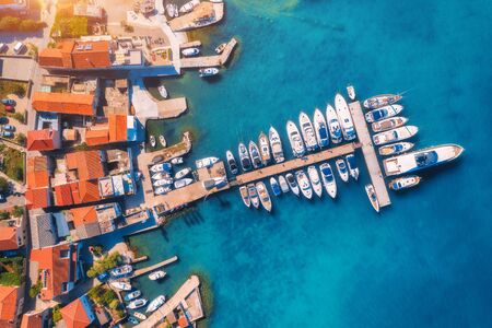 Aerial view of boats and yachts in port in old city at sunset. Summer landscape with buildings with orange roofs, motorboats in harbor, clear blue sea. Beautiful architecture. View from above. Travelの写真素材