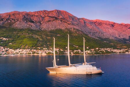 Luxury yacht and blue sea at sunset in summer. Aerial view of big modern sail boat. Top view of...