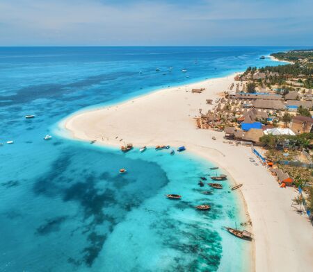 Aerial view of the fishing boats on tropical sea coast with sandy beach at sunset. Summer holiday in Zanzibar, Africa. Landscape with boat, yachts, palm trees, clear blue water and hotels. Top viewの写真素材
