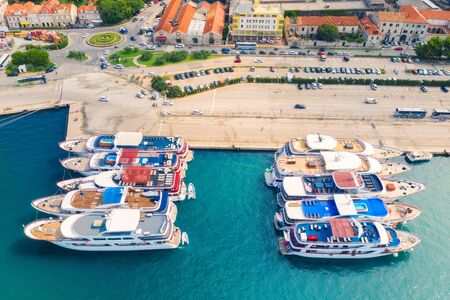 Aerial view of boats and luxury yachts in port at sunset. Summer landscape with buildings with orange roofs, motorboats in harbor, clear blue sea. Beautiful architecture. View from above. Travelの写真素材