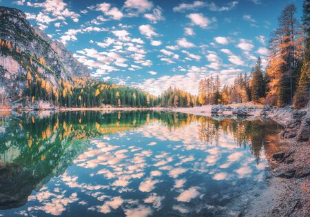 Beautiful reflection in Braies lake at sunrise in autumn in Dolomites, Italy. Landscape with mountains, blue sky with clouds, water, stones, trees with colorful leaves. Lake in fall. Panorama. Natureの写真素材