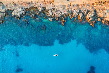 Aerial view of beach with stones and rocks, alone boat in adriatic sea at sunset in summer. Top view of yacht in transparent blue water. Travel in Croatia. Nature background. Landscape with oceanの写真素材