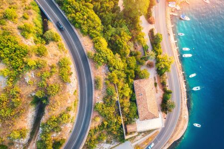 Aerial view of road, boats and yachts in water, buildings at sunset in summer. Colorful landscape with roadway, sea coast, port, green trees in spring. View from above of highway in Croatia. Travelの写真素材