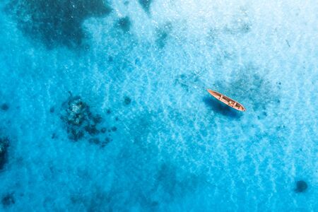 Aerial view of the fishing boat in transparent blue water at sunny day in summer. Top view from...