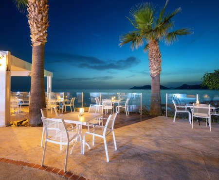 Beautiful cafe on sea coast at night in summer. Chairs and tablesの写真素材
