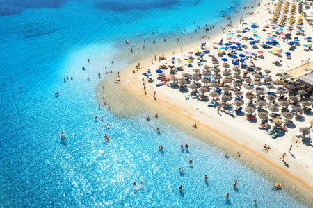 Aerial view of colorful umbrellas on beach, people in blue seaの写真素材
