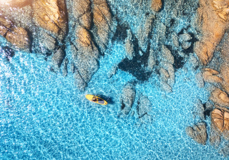 Aerial view of man on floating sup board on blue sea, rocky beachの写真素材