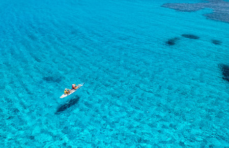 Aerial view of kayak with people in blue sea at sunset in summer