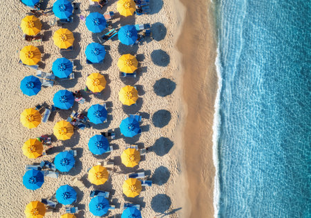 Aerial view of yellow and blue umbrellas on empty sandy beachの写真素材