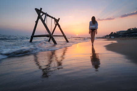 Young woman near wooden swing in water, beautiful blue seaの写真素材