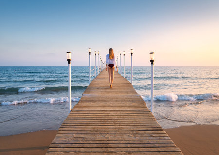 Happy young woman in bikini walking on wooden pier on the seaの写真素材