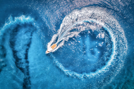 Aerial view of the speed boat in transparent blue water at sunsetの写真素材
