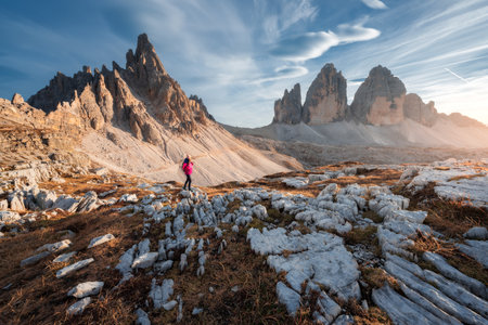 Walking girl with backpack on the trail in mountains at sunsetの写真素材