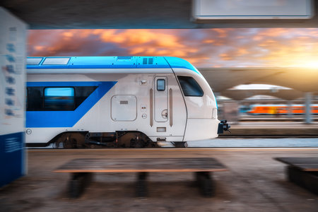 Blue high speed train in motion on the railway station at sunset