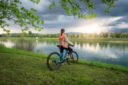 Woman riding a mountain bike near lake and blue sky in springの写真素材