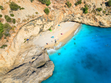 Aerial view of wild beach, blue sea, rock, umbrellas in summerの写真素材