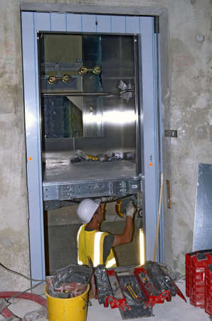 Besançon, France - July 17, 2014: Technician installing the cabin of an elevator on a construction site.のeditorial素材