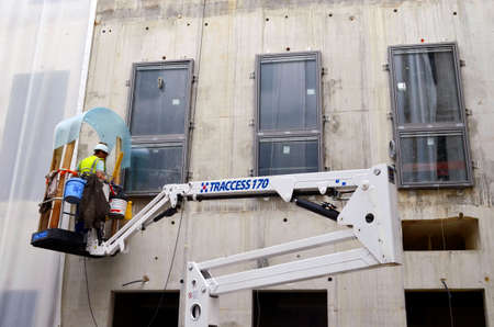 Besançon, France - November 3, 2014: Construction workman on a cherry picker installing windows on a construction site.のeditorial素材
