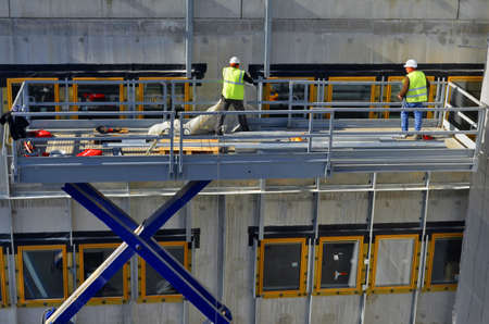 Besançon, France - March 9, 2015: Construction workmen on a cherry picker installing windows on a construction site.のeditorial素材